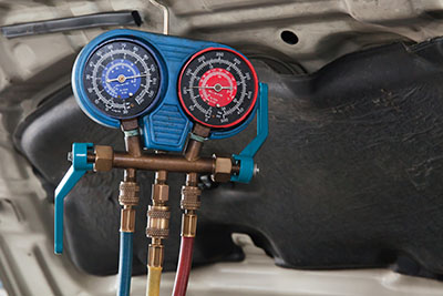 Mobile mechanic in Albuquerque repairing and recharging a car's AC components on-site
