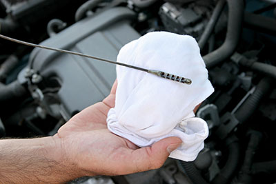 Mobile mechanic in Albuquerque checking engine oil level during a mobile oil change service

