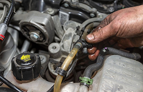 Mobile mechanic in Albuquerque inspecting engine coolant hoses during an on-site auto repair
